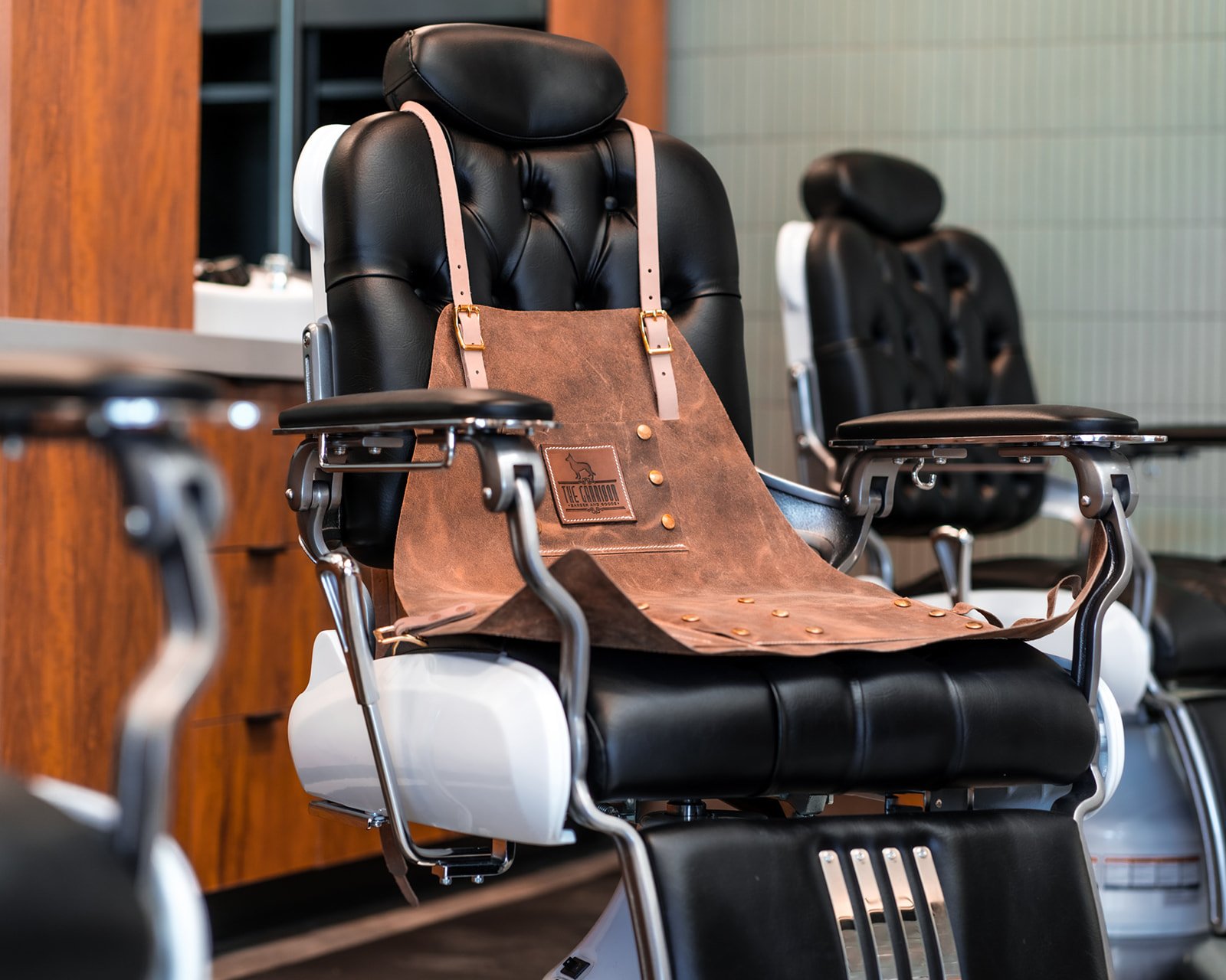 A leather apron draped over the arm of a barber chair